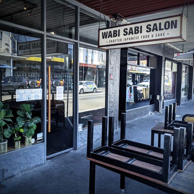 Exterior of Wabi Sabi Salon shopfront in Collingwood, Melbourne, viewed from the street with signage, windows, and outdoor seating area.